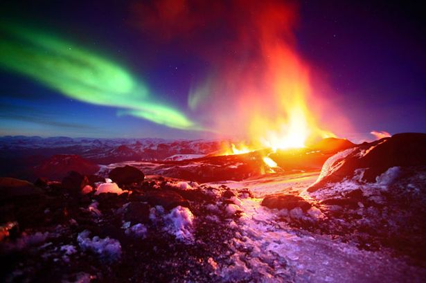 Volcanic eruption on the Fimmvruhls mountain pass, with Aurora Borealis display in the sky behind